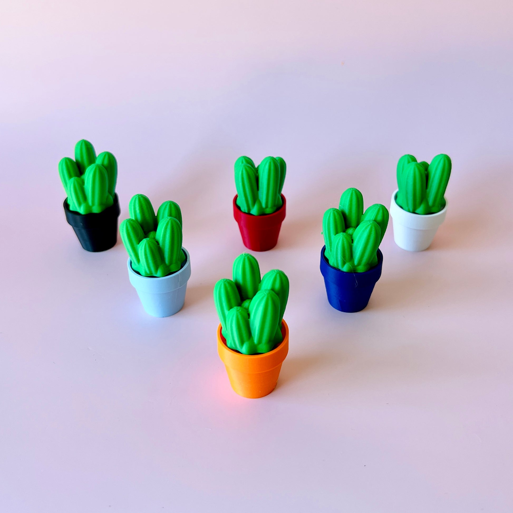 Colorful miniature cactus plants in various pots against a light background, showcasing vibrant green and playful designs.