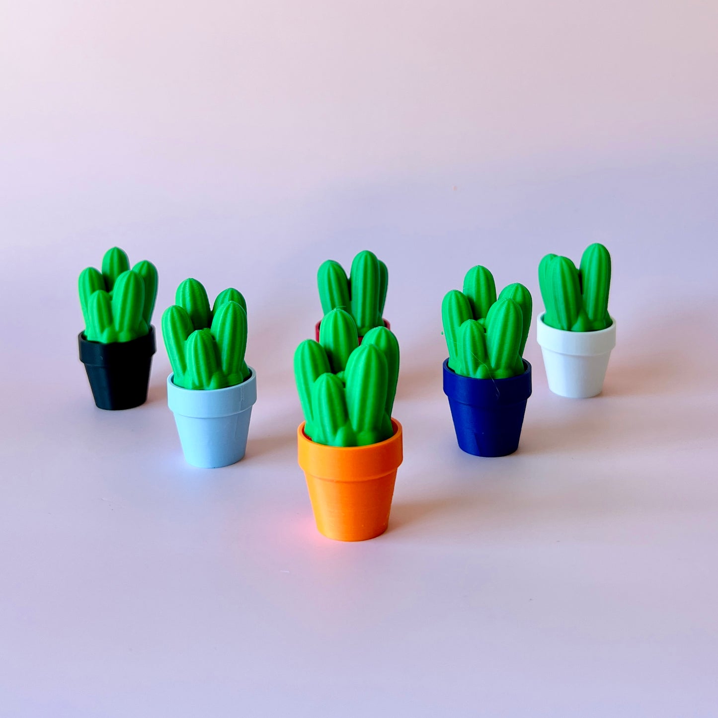 Colorful pots with vibrant green cacti arranged on a light background, creating a playful, cheerful display.