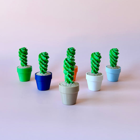 Colorful miniature potted plants with spiral green tops arranged against a soft pink background.