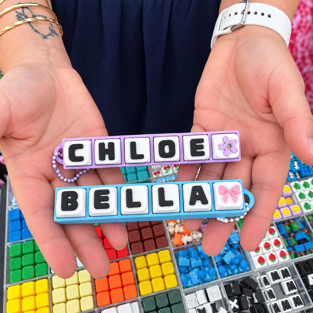 6 Key Fidget Clicker, 3D printed fidget clicker in black and blue with personalised name keycaps, held in hands