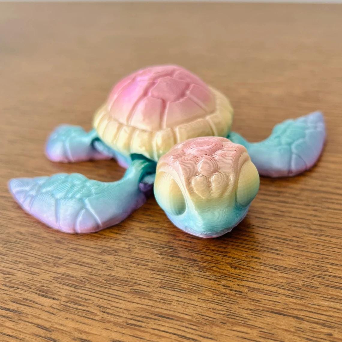 Colorful 3D-printed sea turtle figurine with detailed shell and flippers, resting on a wooden surface.