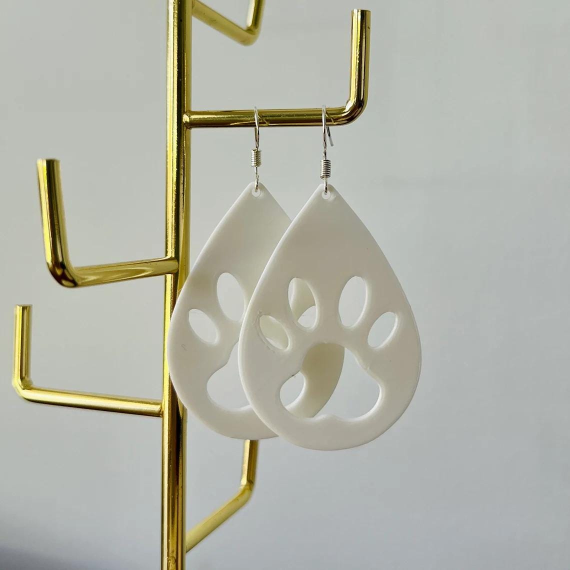 White paw print dangle earrings with sterling silver hooks, showcasing a playful yet elegant design, perfect for everyday wea