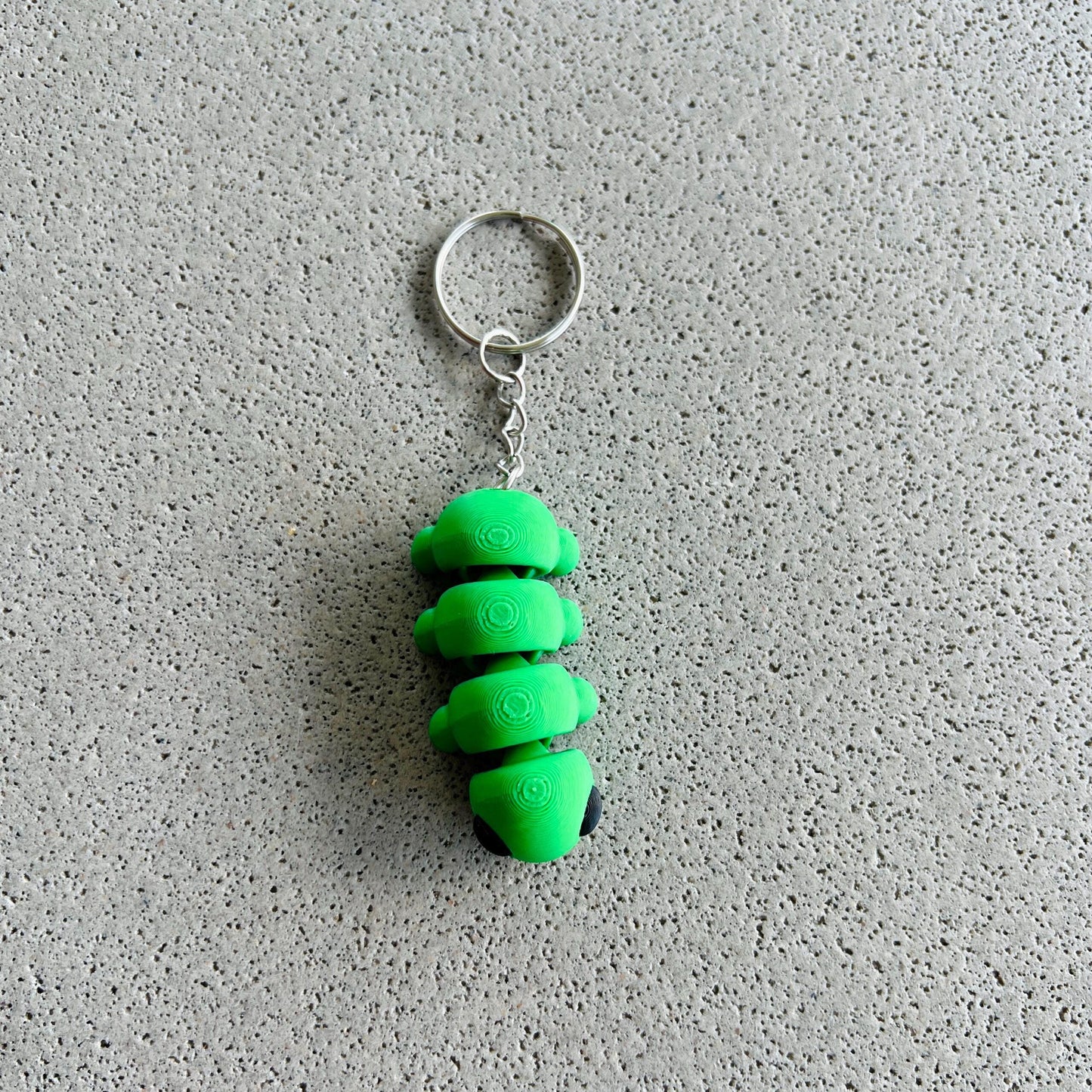 Whimsical green caterpillar keychain with a silver ring, perfect for adding charm to keys or bags.