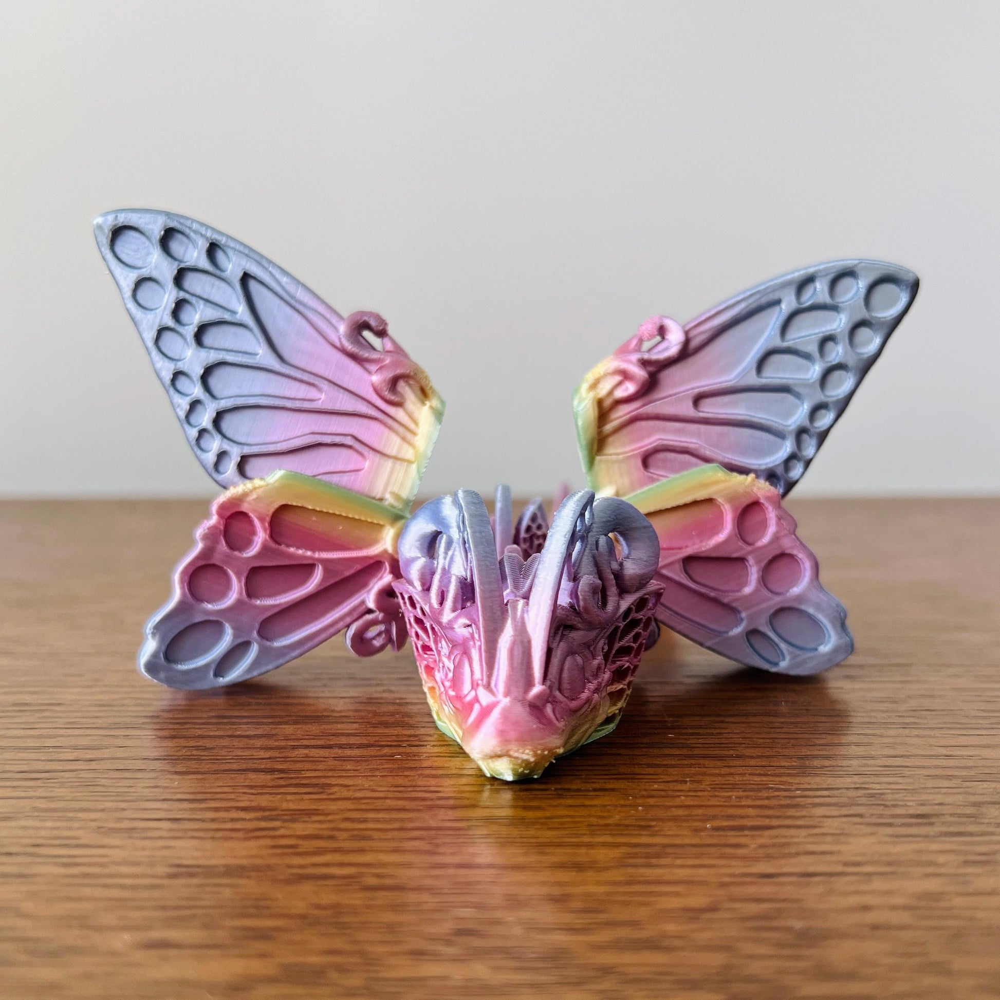 Colorful dragon with intricate butterfly wings, blending whimsy and fantasy on a wooden surface.