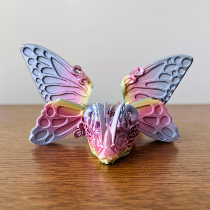 Colorful dragon with intricate butterfly wings, blending whimsy and fantasy on a wooden surface.
