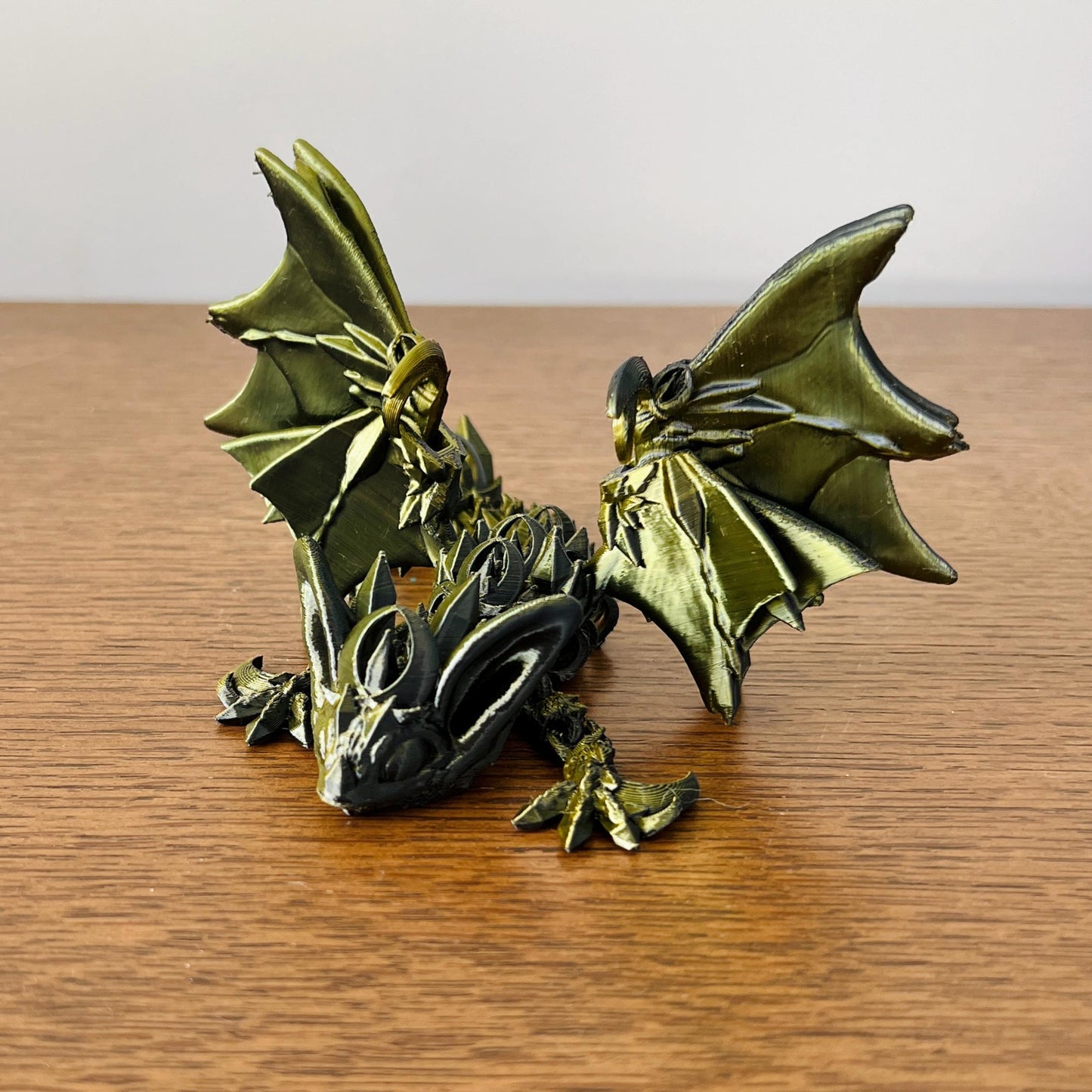 Sleek dark dragon with bat-like wings and intricate details, evoking the allure of the night, resting on a wooden surface.
