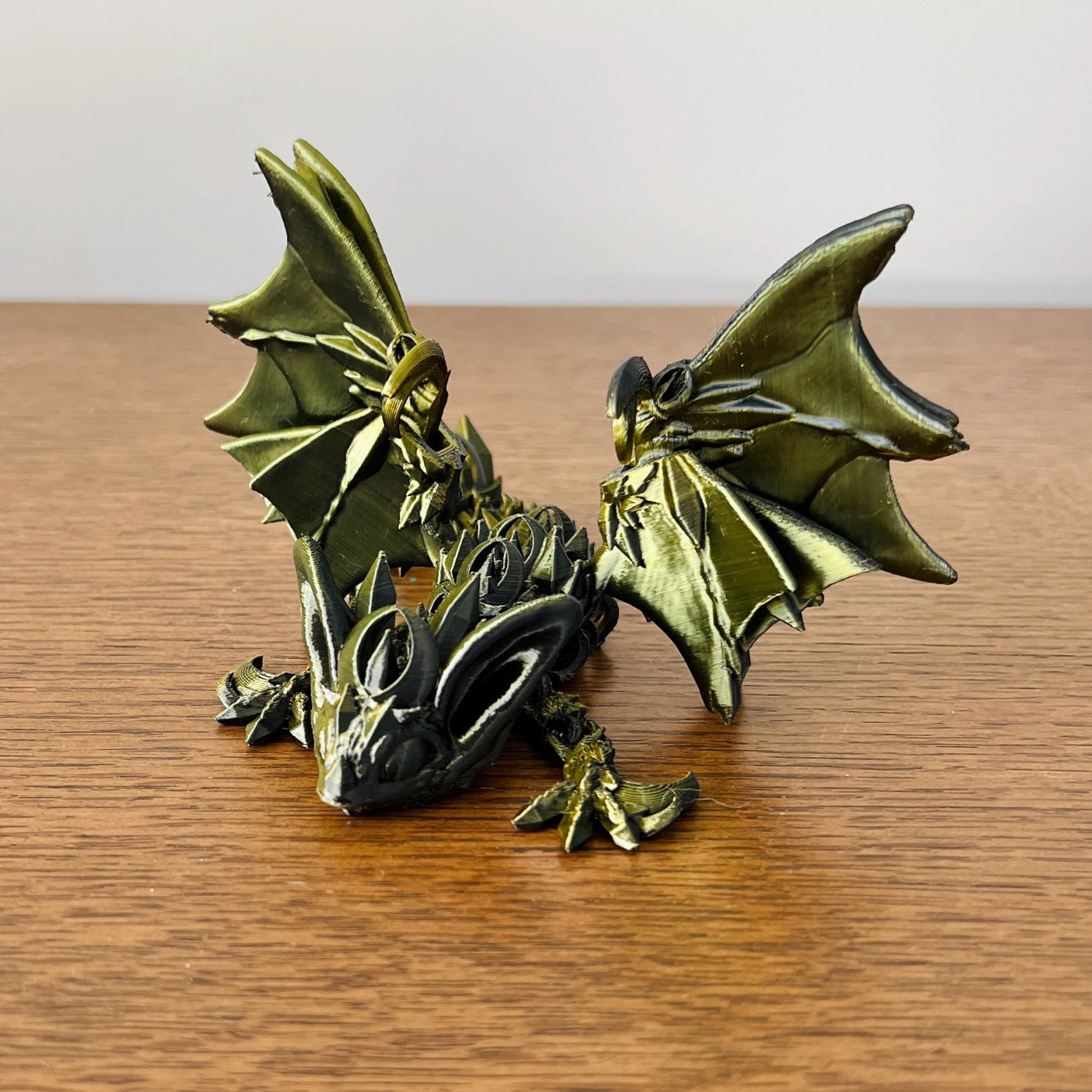 Sleek dark dragon with bat-like wings and intricate details, evoking the allure of the night, resting on a wooden surface.