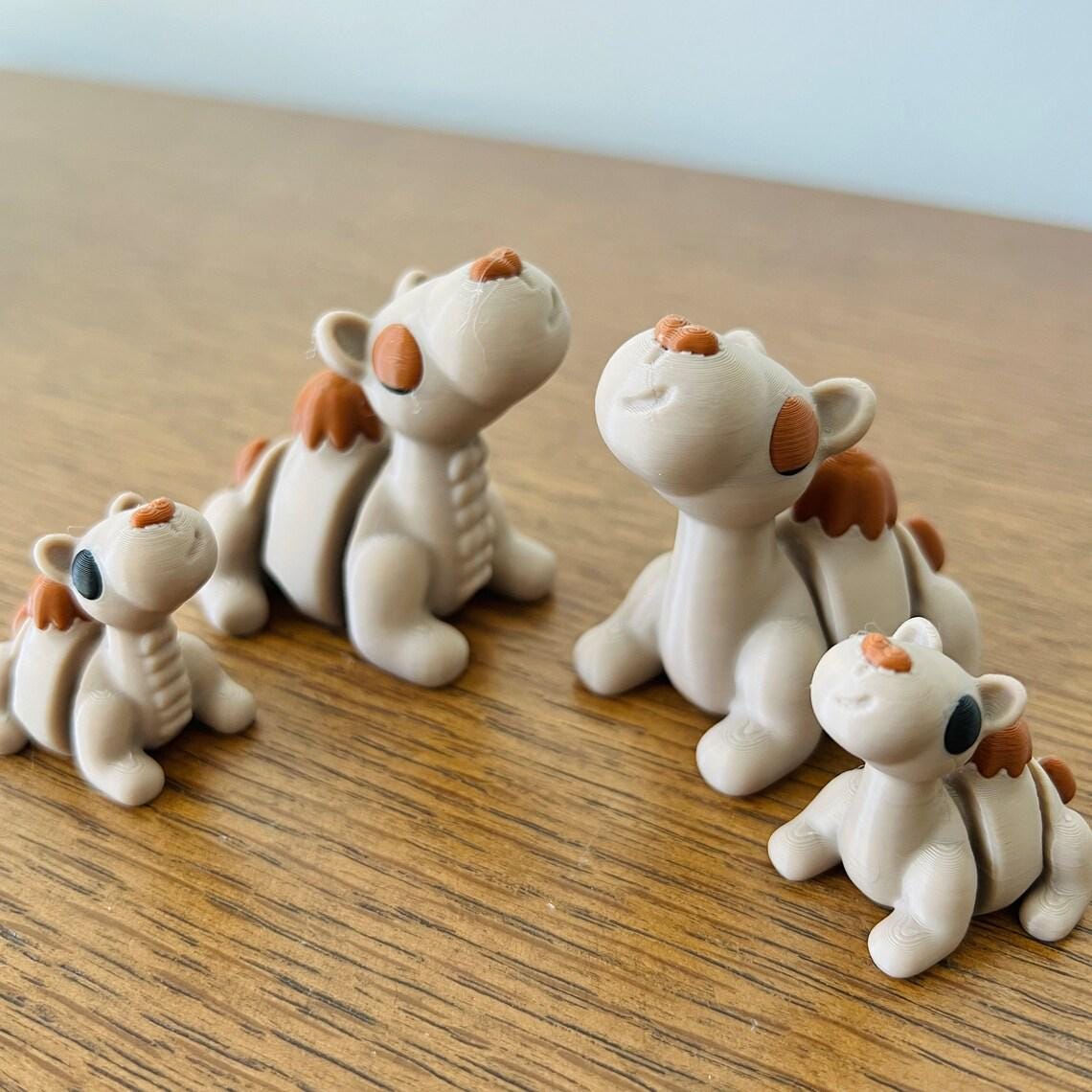 Charming 3D printed camels in various sizes, featuring playful expressions and eco-friendly materials on a wooden surface.