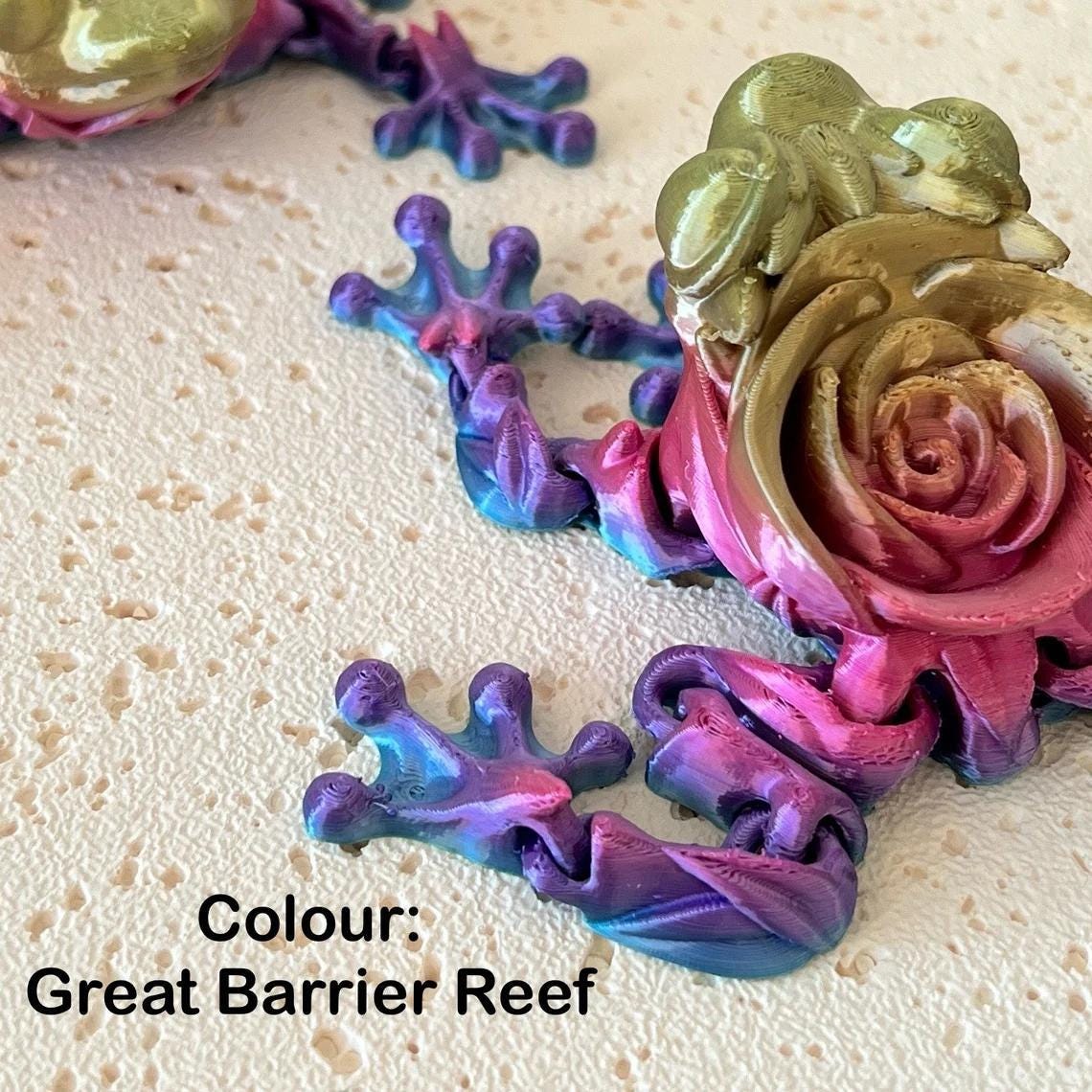 Articulated rose frog figurine in vibrant hues of pink, purple, and green, showcasing intricate details and a floral design.