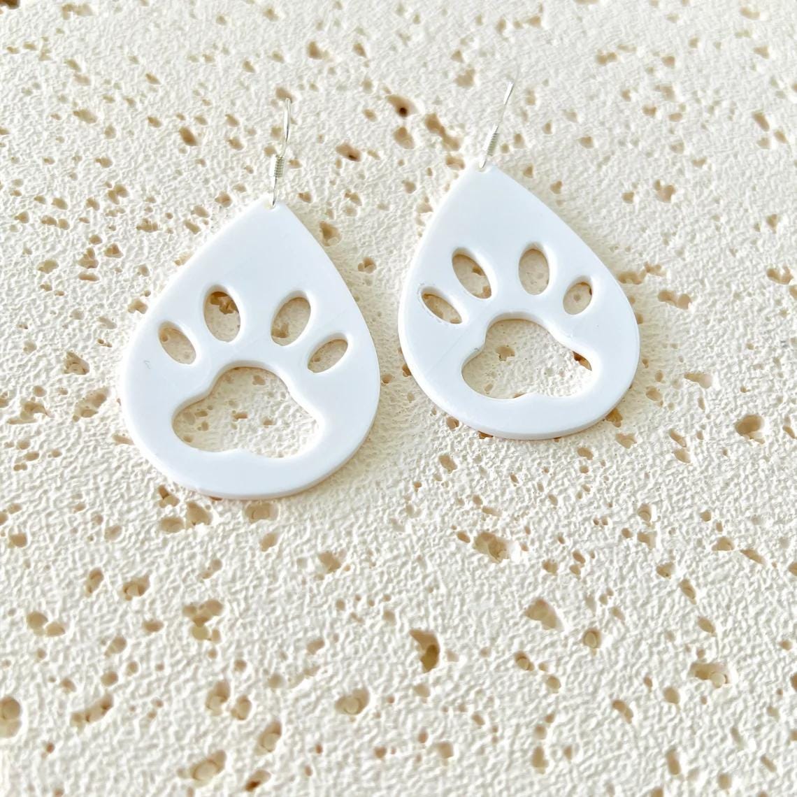 White paw print dangle earrings featuring sterling silver hooks, perfect for adding charm to any outfit.
