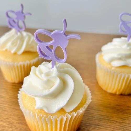 Adorable purple bee toppers perched atop frosted cupcakes, perfect for celebrations and bee-themed events.