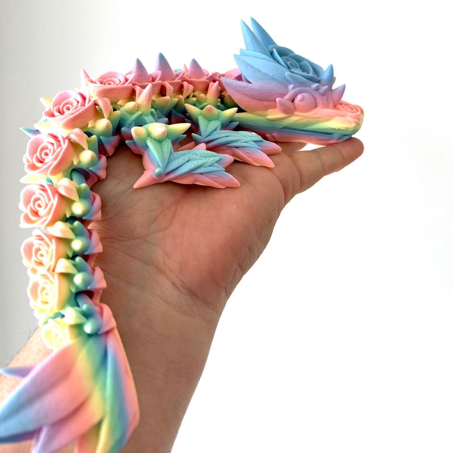 Vibrant Baby Rose Dragon with intricate rose details, cradled in a hand, showcasing its enchanting pastel colors.