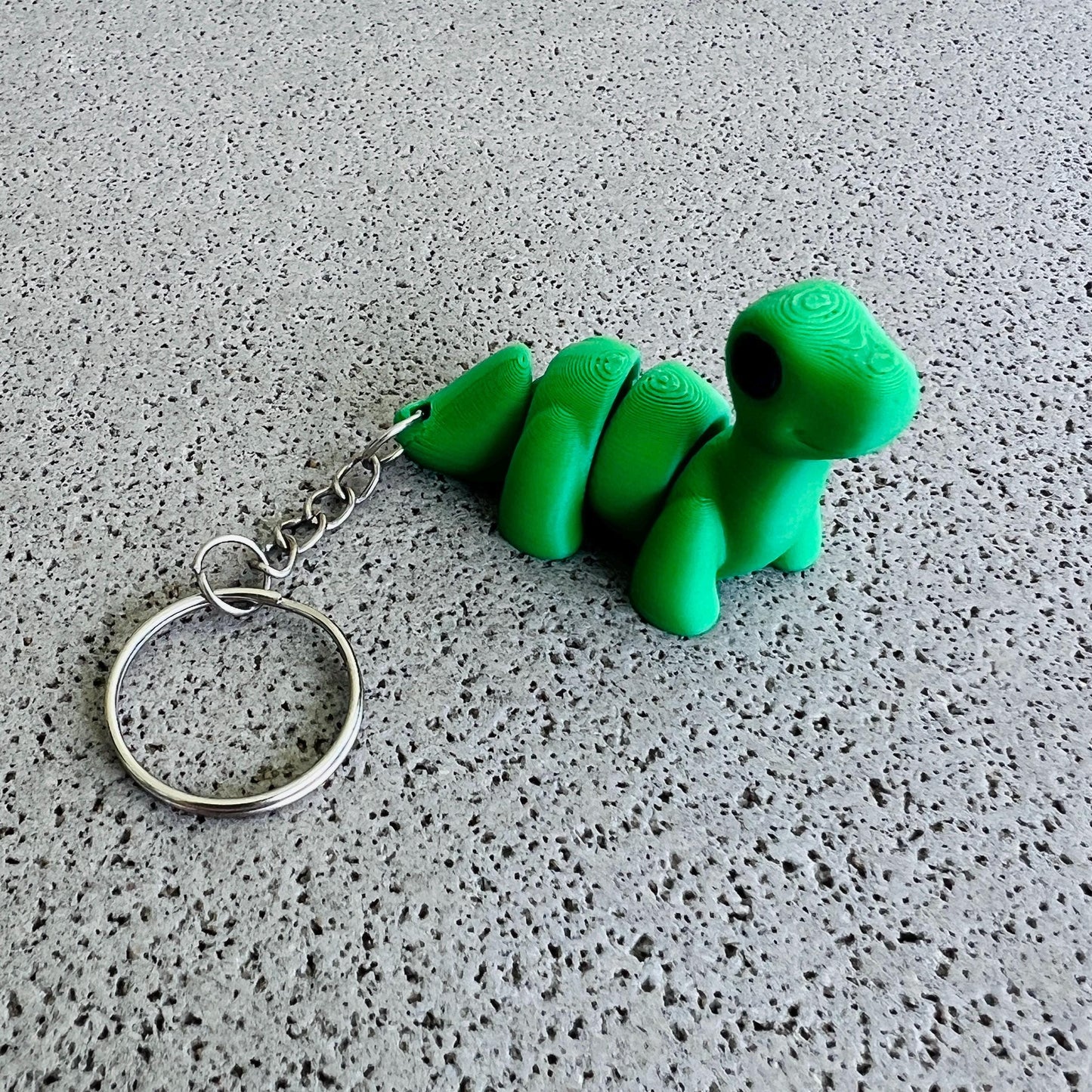 Charming green Brontosaurus keychain with a shiny keyring, perfect for adding flair to bags or keys. Ideal for dino lovers!