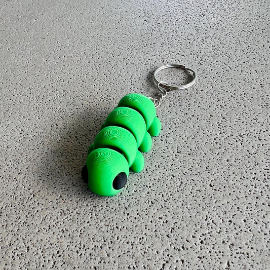 Vibrant green caterpillar keychain with large black eyes, perfect for adding charm to keys or bags.