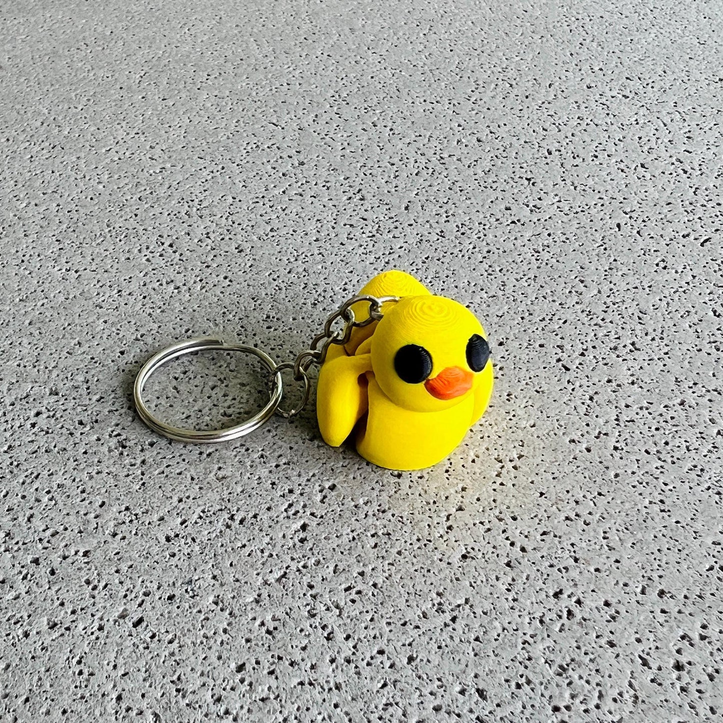 Bright yellow duck keychain with big black eyes and an orange beak, perfect for adding fun flair to keys or bags.