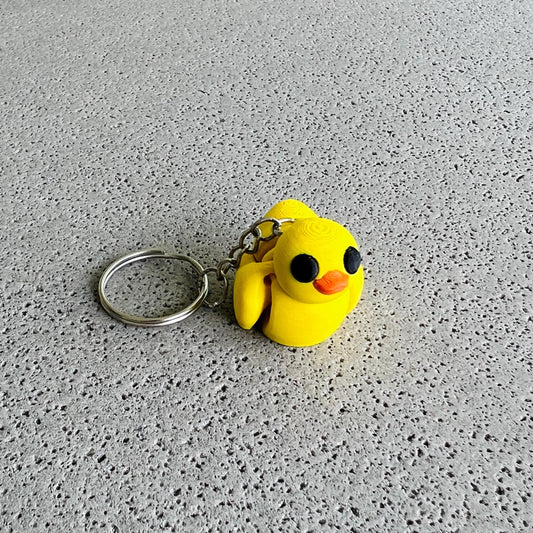 Bright yellow duck keychain with big black eyes and an orange beak, perfect for adding fun flair to keys or bags.