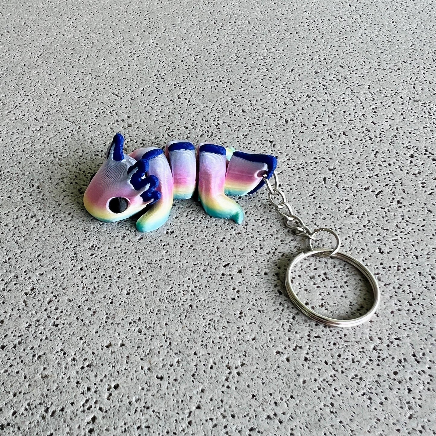 Vibrant rainbow axolotl keychain featuring pastel colors and a playful design, perfect for brightening up your belongings.